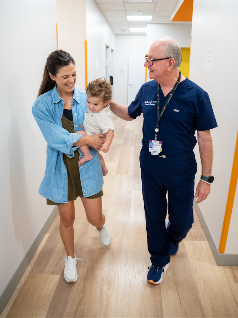 Urologist walking down a hallway with a mother and child post-appointment