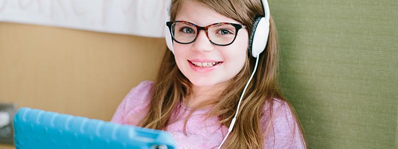 Melissa is listening to an audio book while in her hospital room.