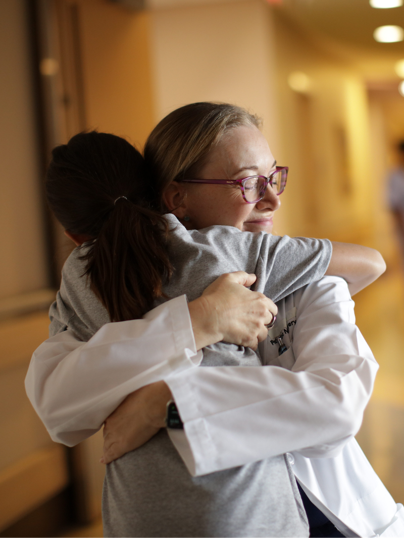 Behavioral health specialist hugging a pediatric patient