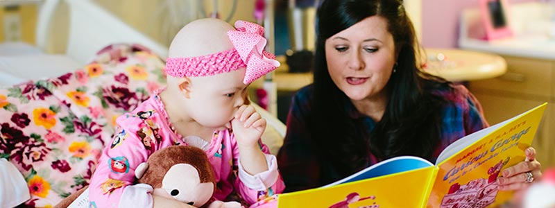 Elizabeth's mom is reading a book to her while she is in the hospital. The book was a donation from another patient family.
