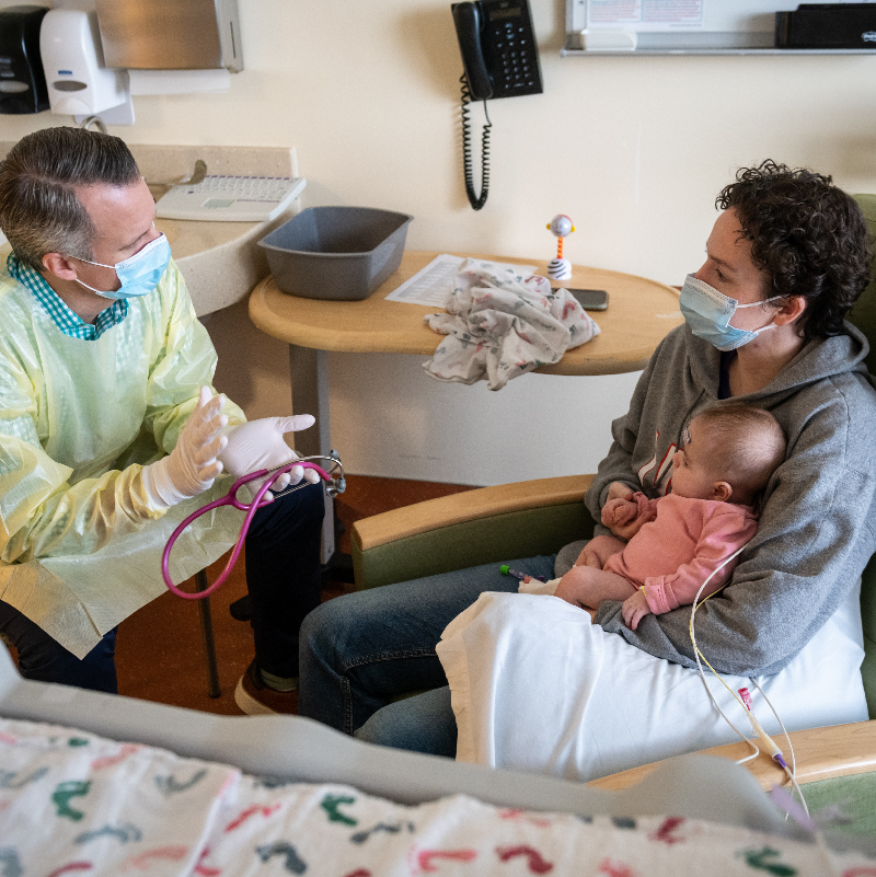 parent holding baby while speaking with physician
