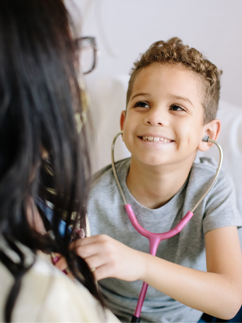 Pediatric patient smiling and using a stethoscope
