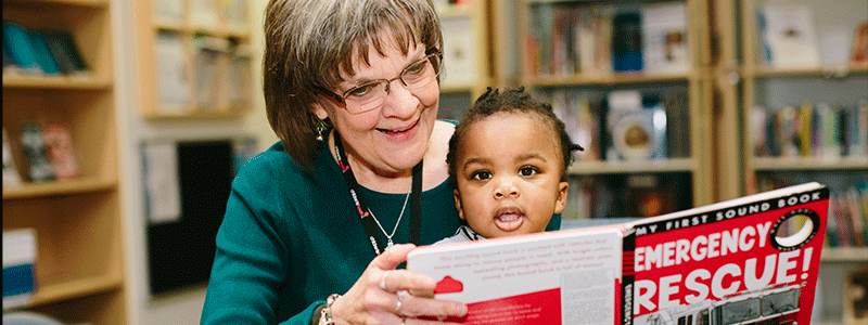 Librarian Carol Miller with patient David reading in the library at Children's Health.