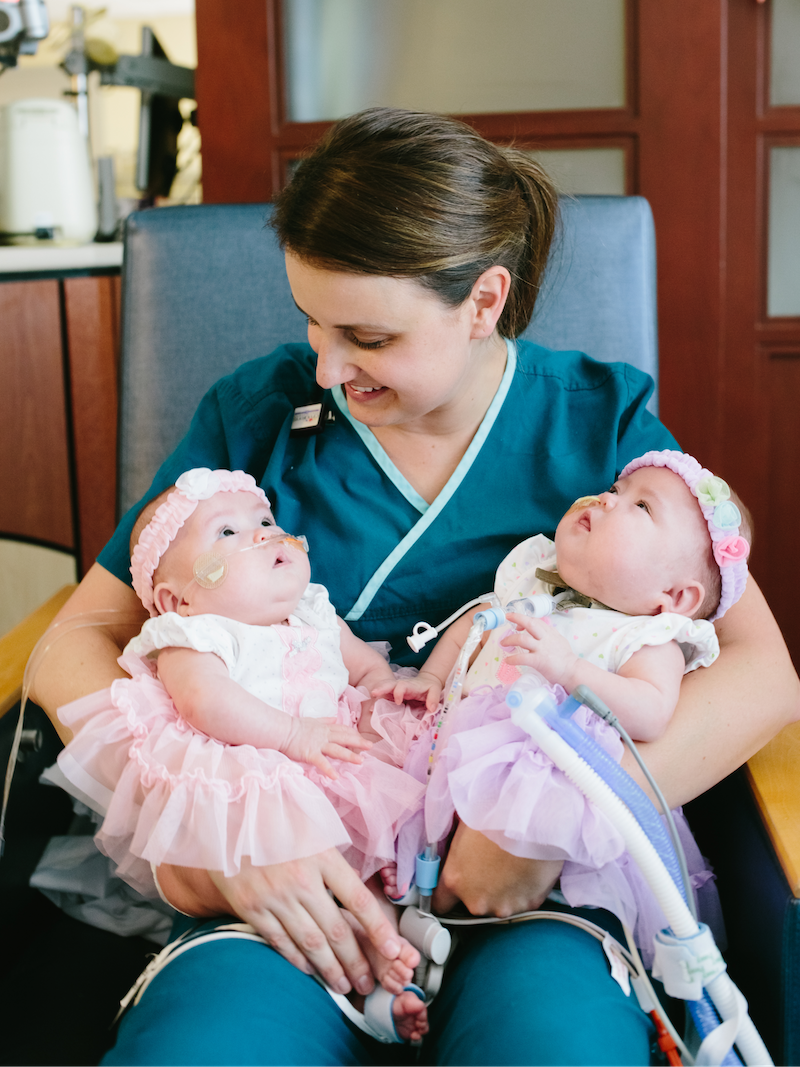 Neonatologist holding and looking down at twin babies from the NICU