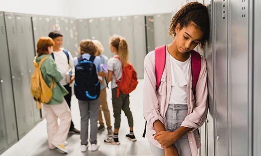 little girl standing alone while a group of kids are together.